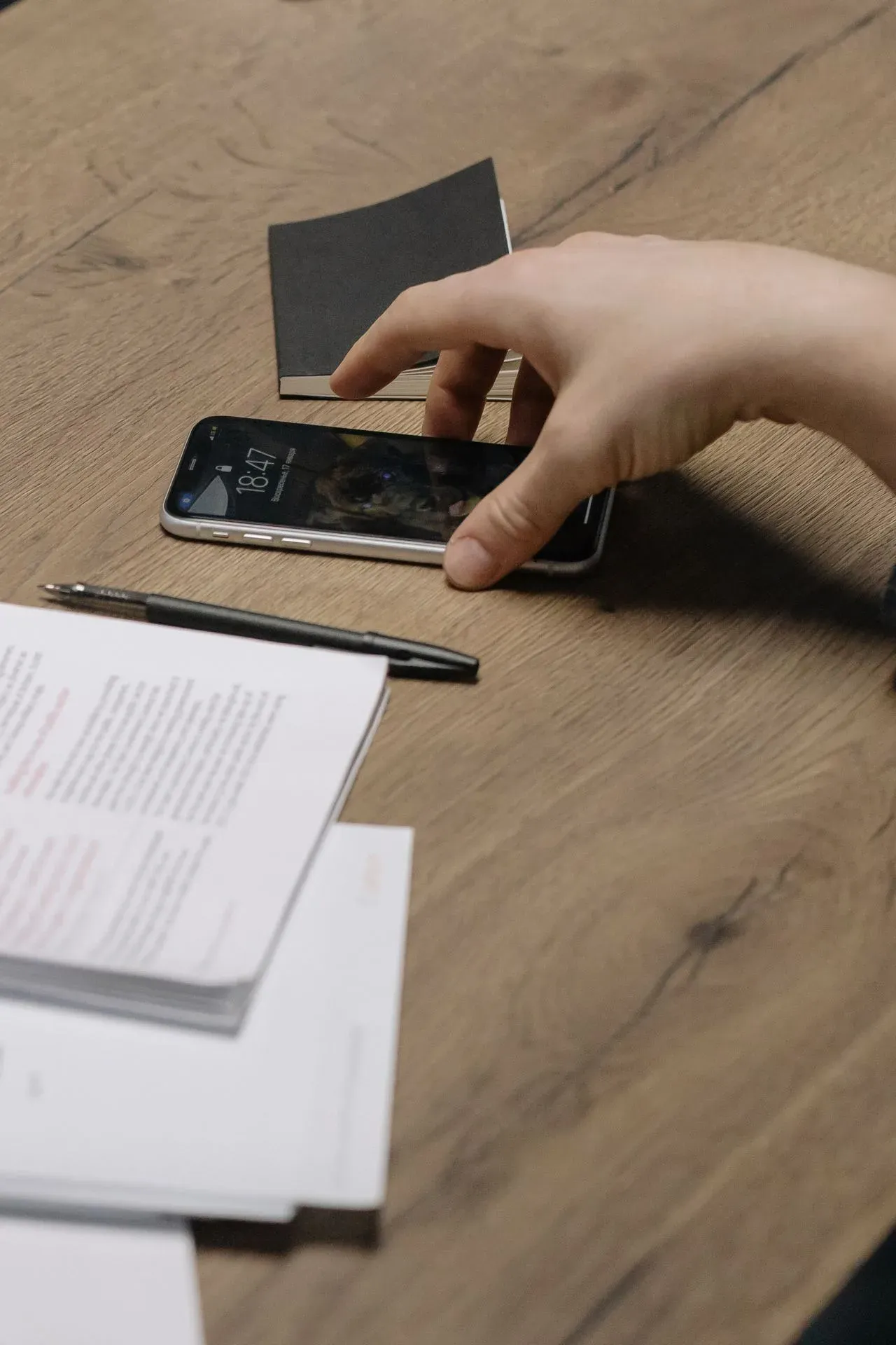 Una mano prende uno smartphone appoggiato su un tavolo